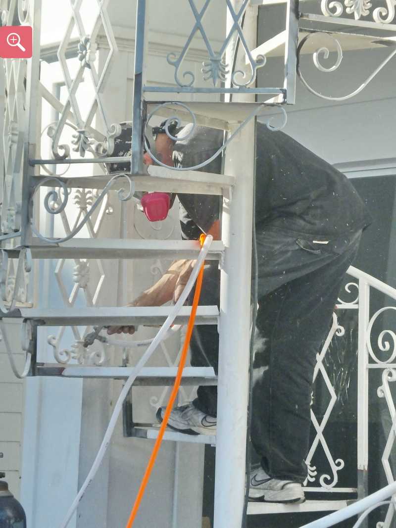 Sandblasting rusty steel spiral stair case for repair