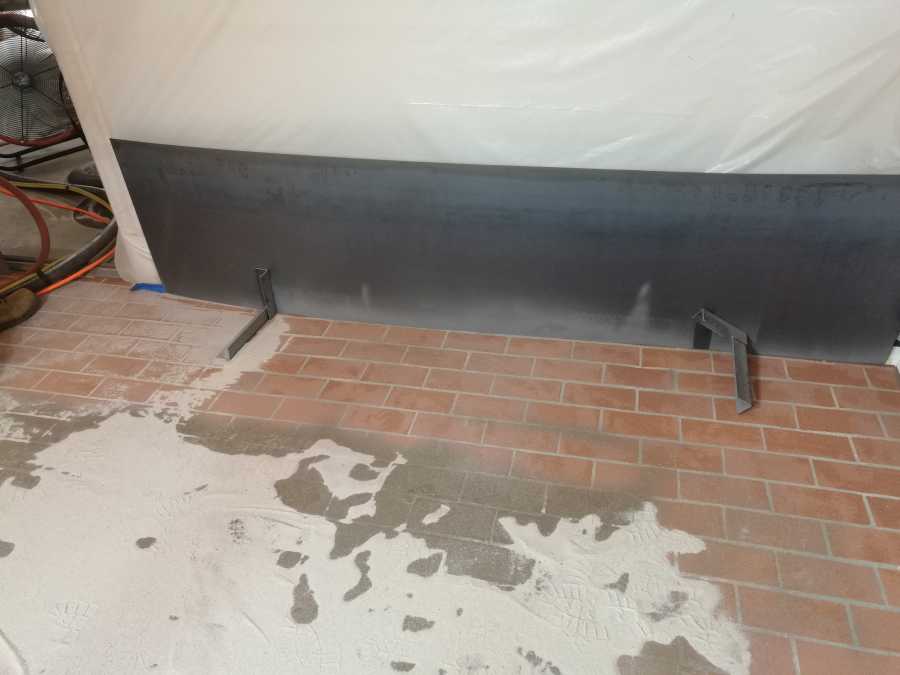 Sandblasting paint off a brick floor while protecting baseboards. 
